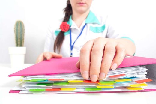 Una mujer sostiene una carpeta rosa con pestañas de colores.