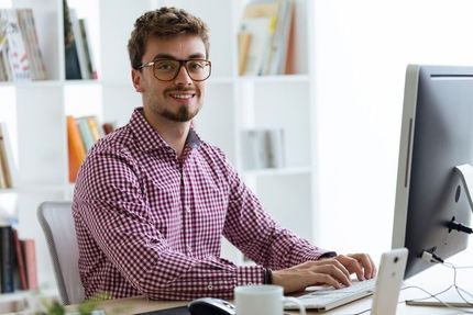 Un hombre está sentado en un escritorio frente a una computadora.