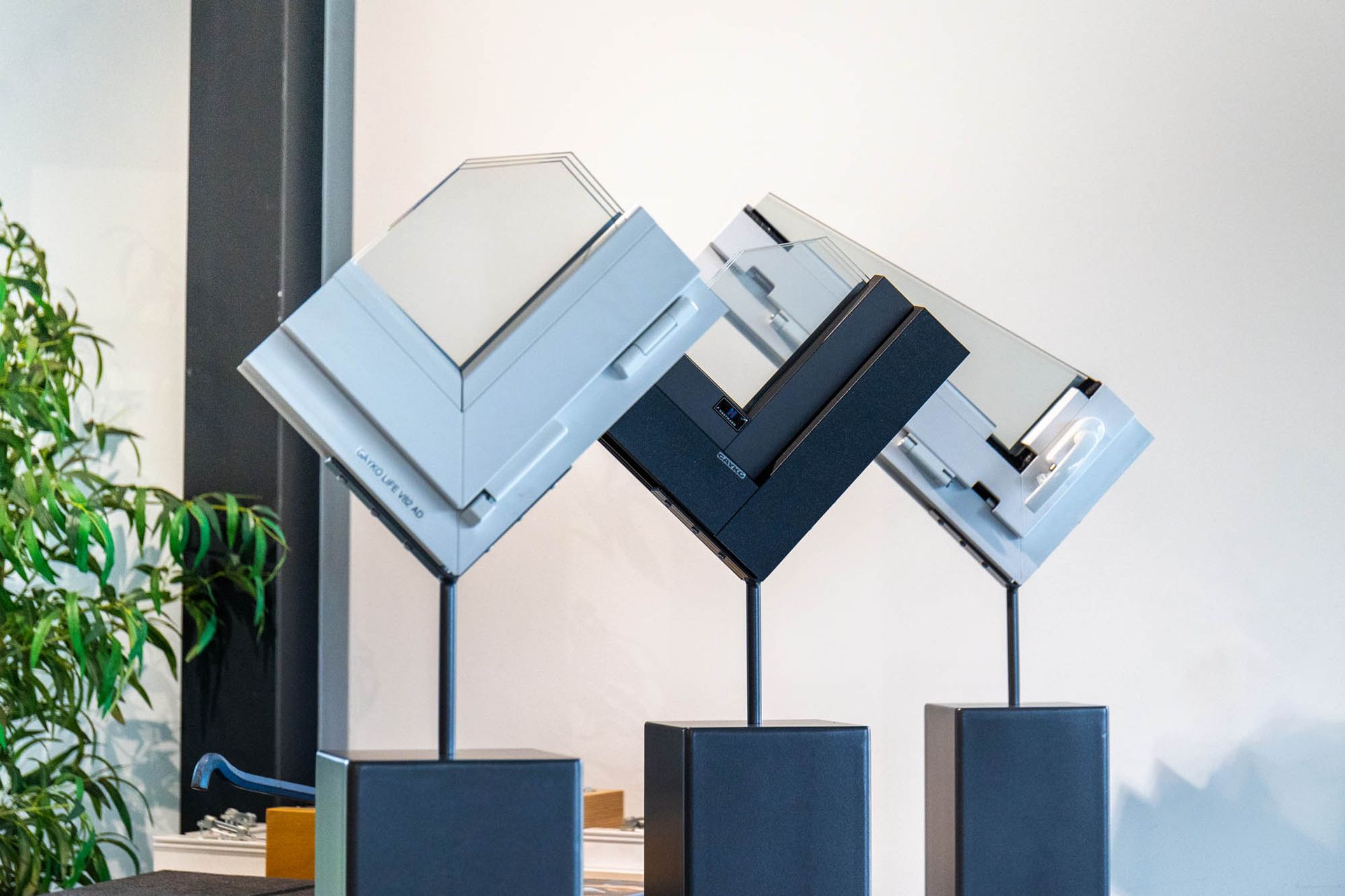 Auf einem Tisch stehen drei Skulpturen mit verschiedenfarbigen Fenstern.