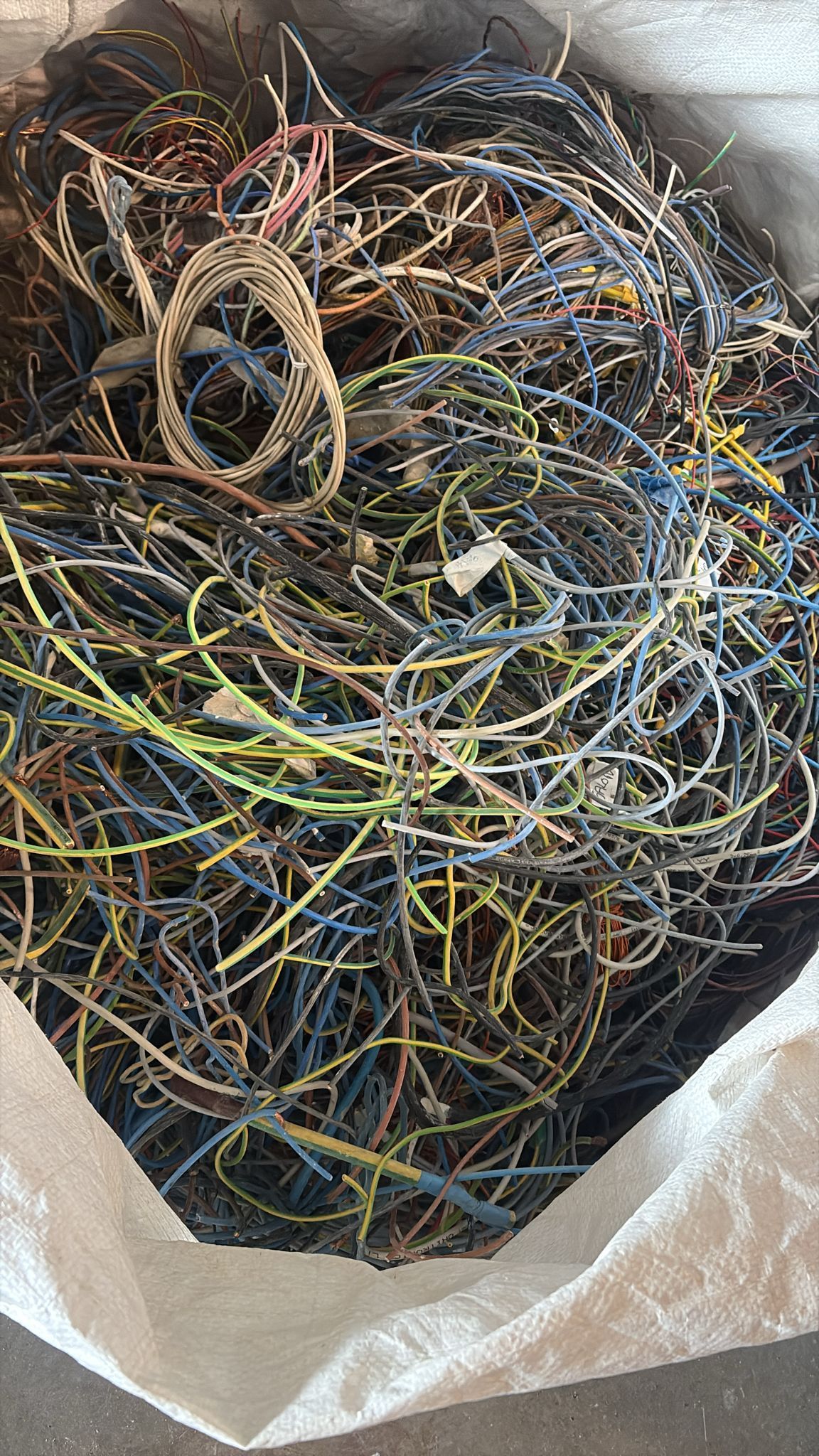 Bolsa llena de una masa enredada de cables eléctricos de colores, probablemente para reciclar.