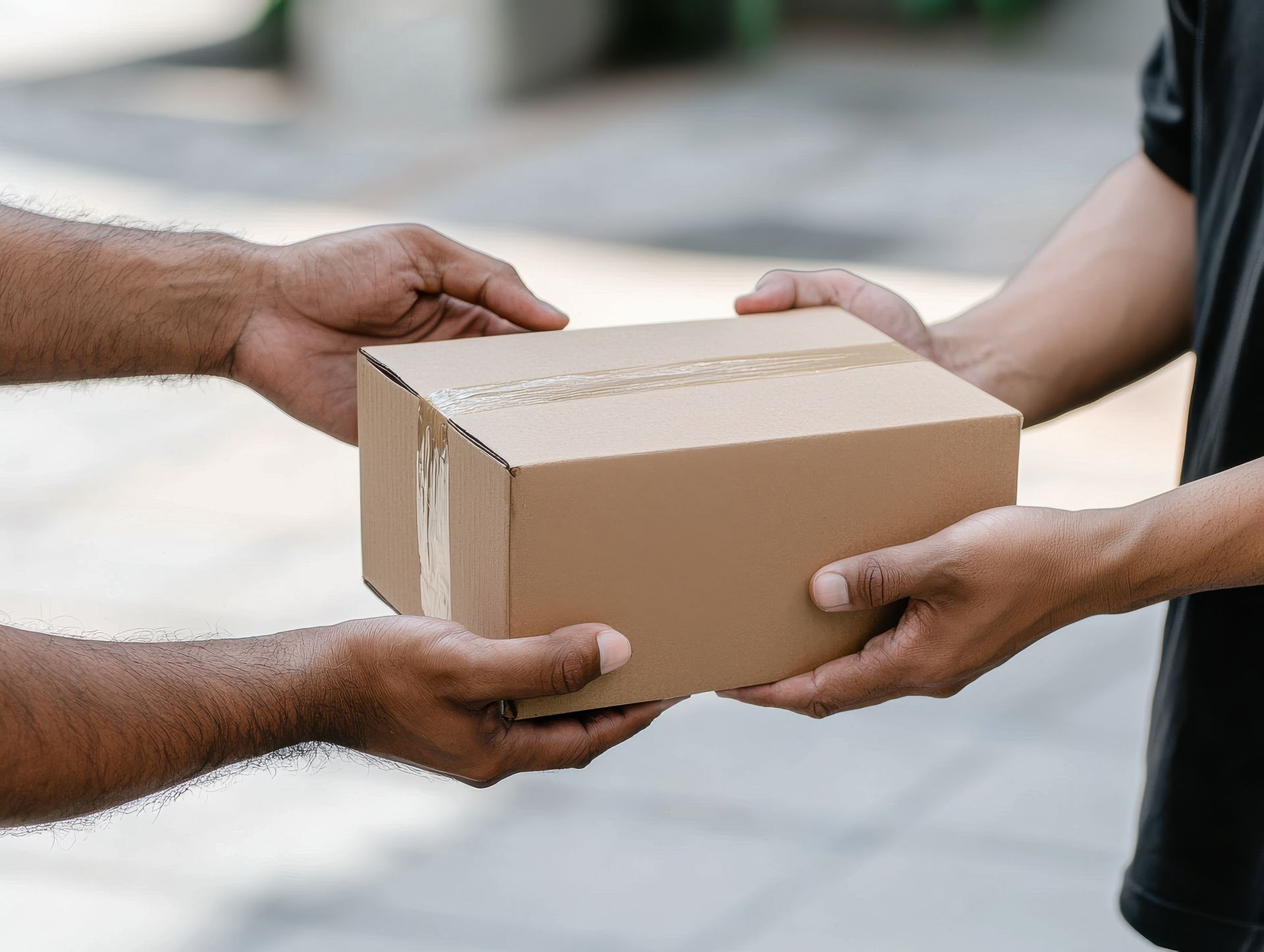 Deux personnes tenant un paquet en carton à l'extérieur.