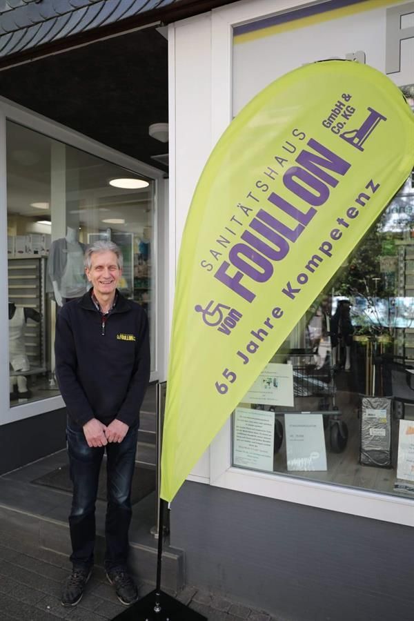 Ein Mann steht vor einem Geschäft mit einem Banner mit der Aufschrift „Foillon“