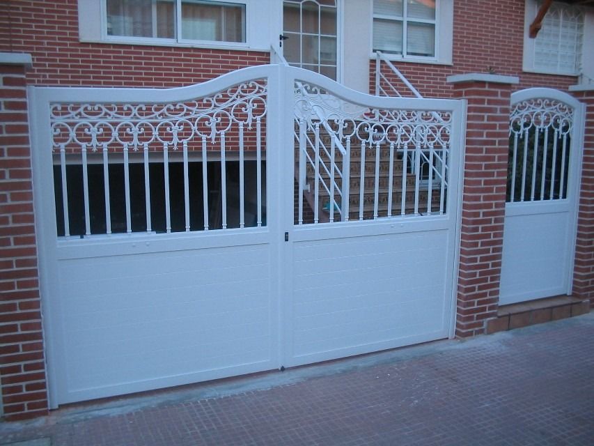 Puerta doble de hierro forjado blanco y ladrillo frente a un edificio de ladrillo.