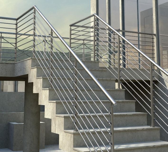 Escaleras exteriores de hormigón con barandillas de metal plateado junto a un edificio.