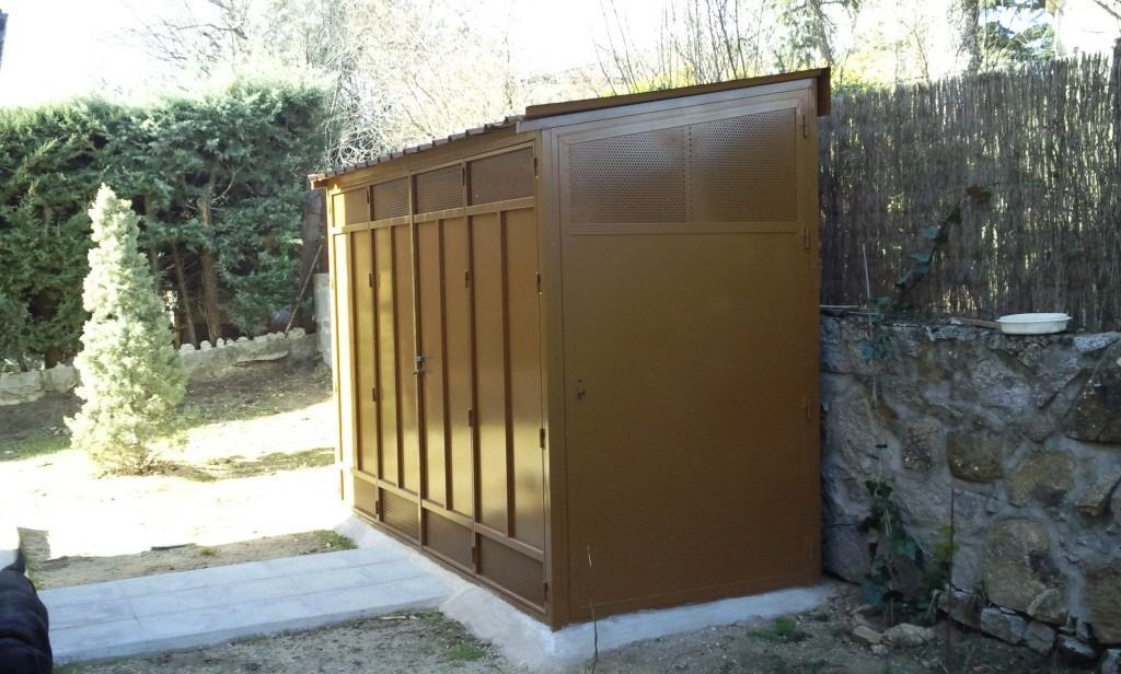 Caseta de metal marrón junto a un muro de piedra en un patio trasero soleado.