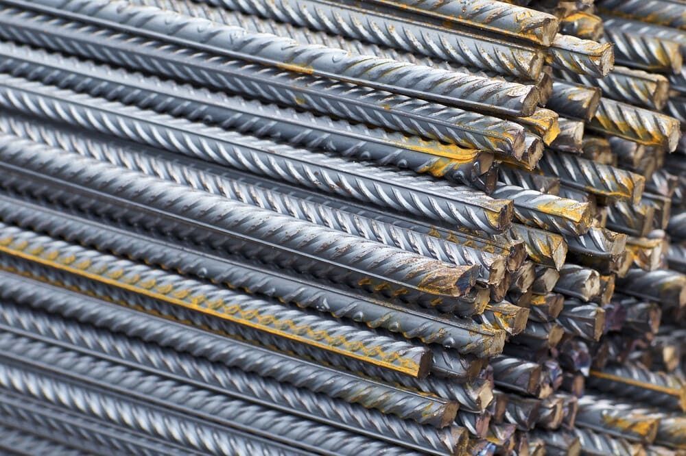 Varillas de metal corrugado plateado apiladas y agrupadas con bridas amarillas