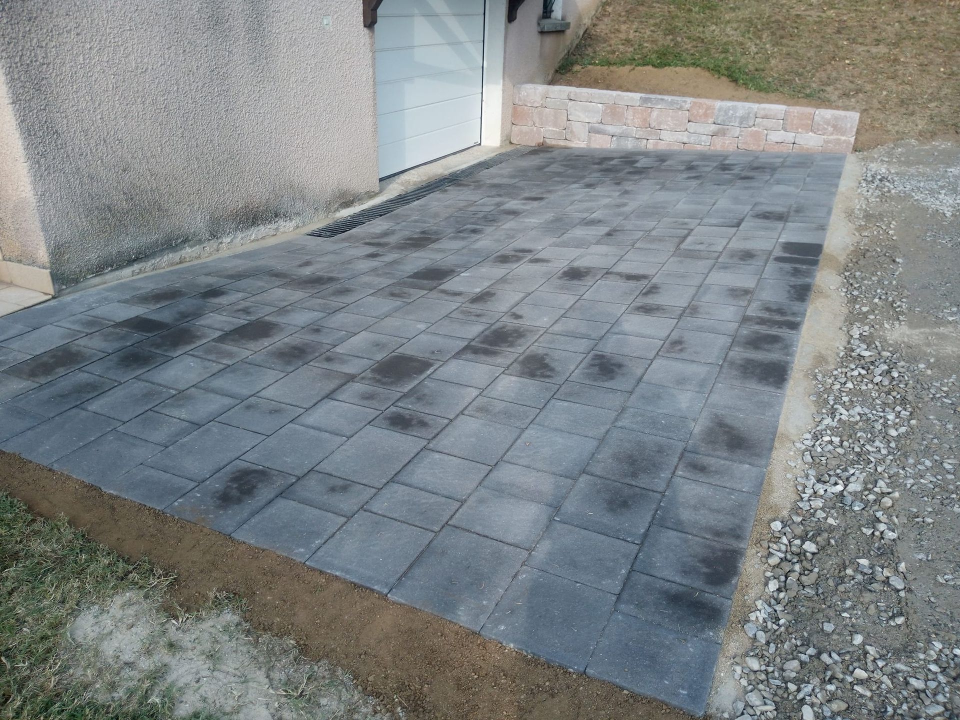 Maison avec escalier, allée et jardin sous un ciel partiellement nuageux.