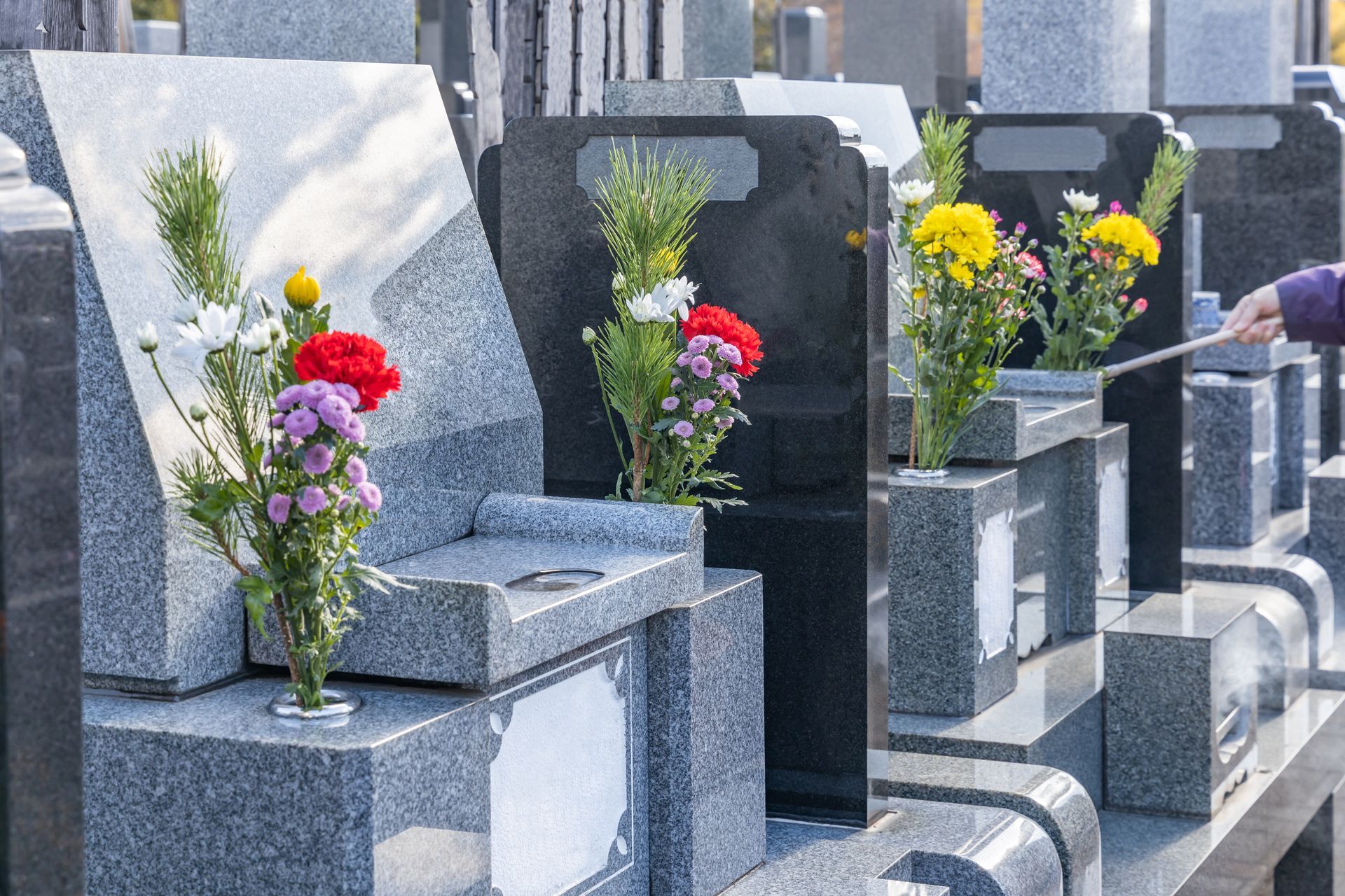 Des rangées de tombes en granit ornées de fleurs.