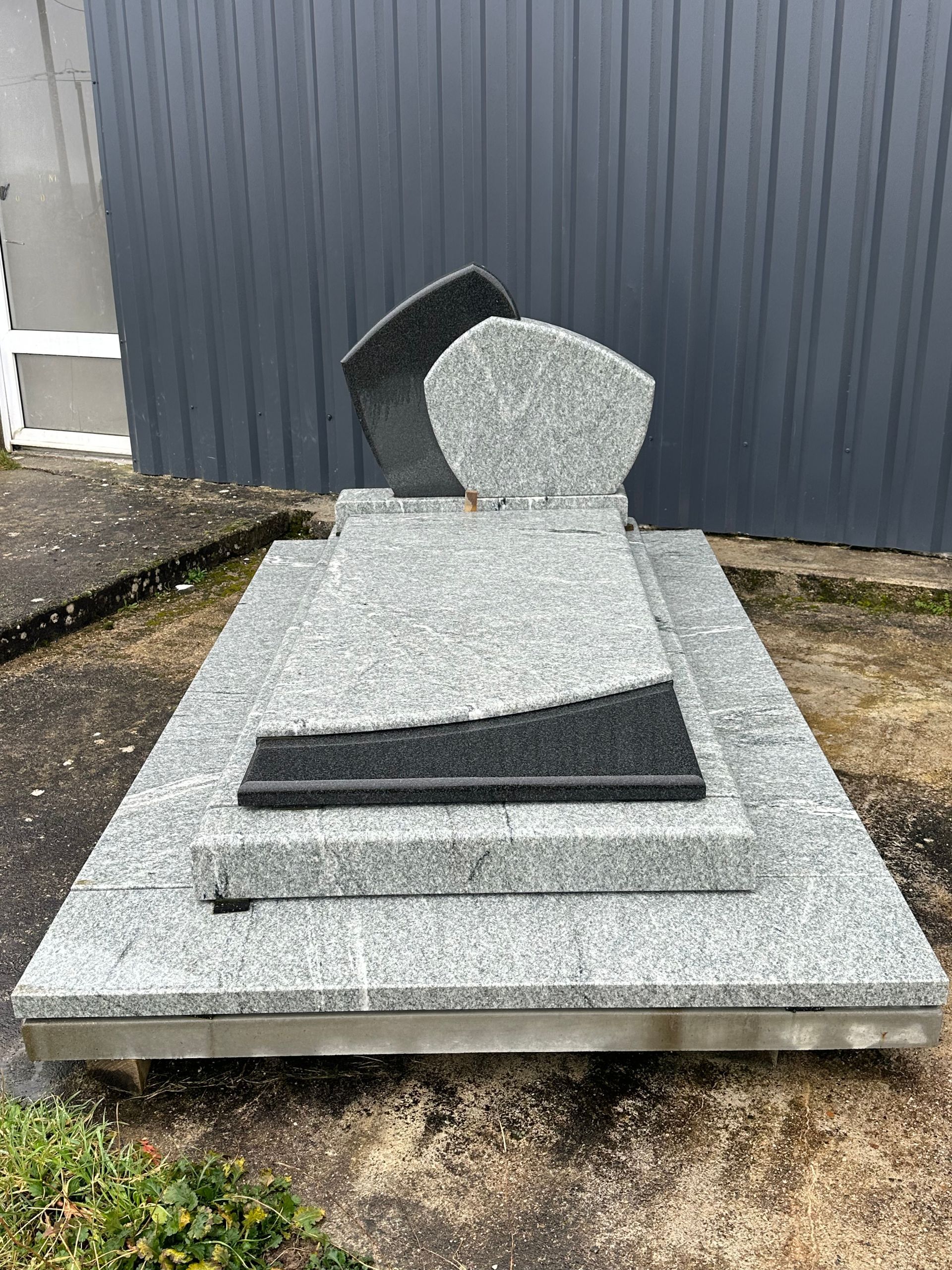 Monument funéraire en granit noir et gris.