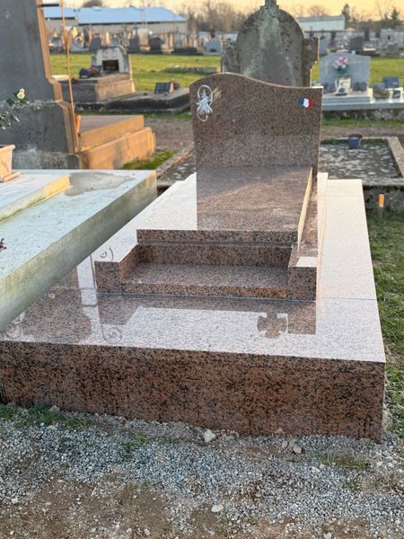 Une sépulture en granit avec une gravure et un drapeau français.