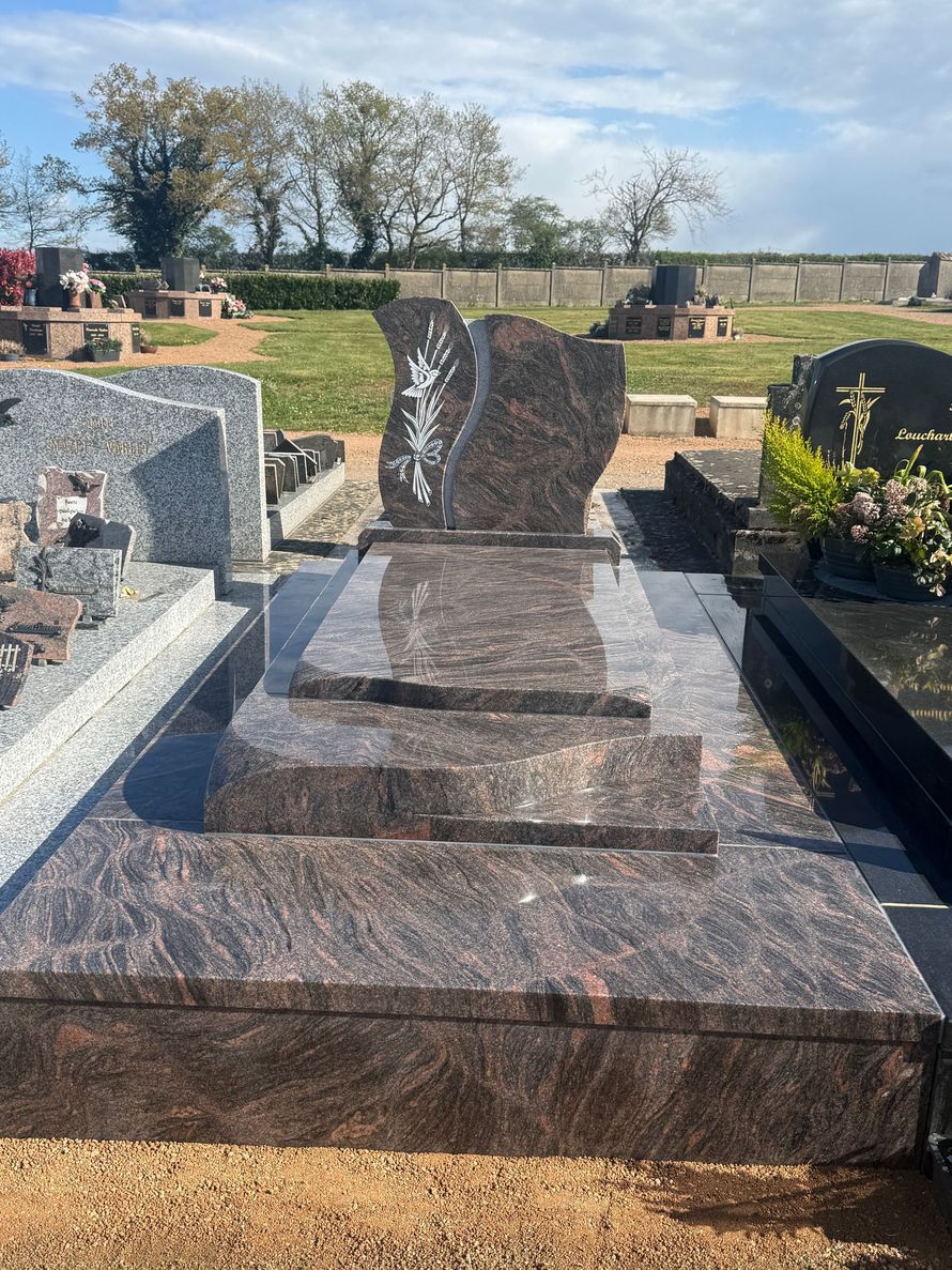 Sépulture en granit avec une gravure d'un épi de blé et un oiseau.