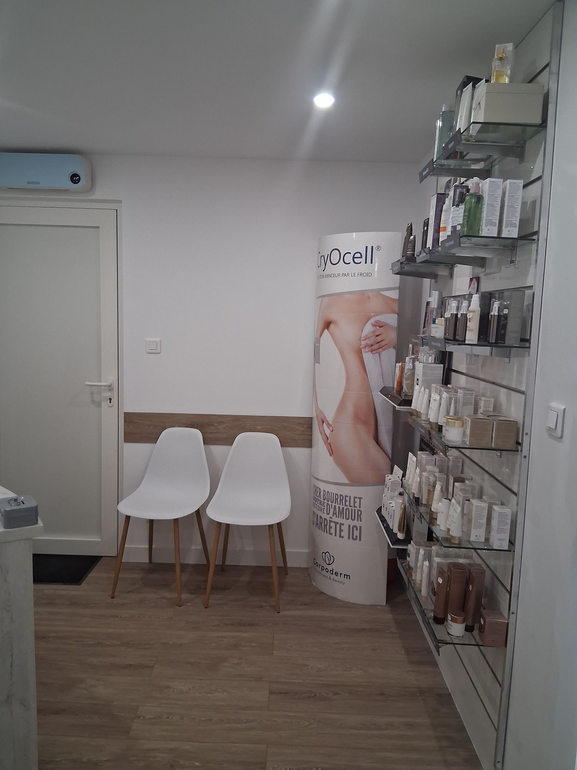 Salle d'attente : deux chaises blanches, étagères de présentation de produits, bannière promotionnelle et porte.