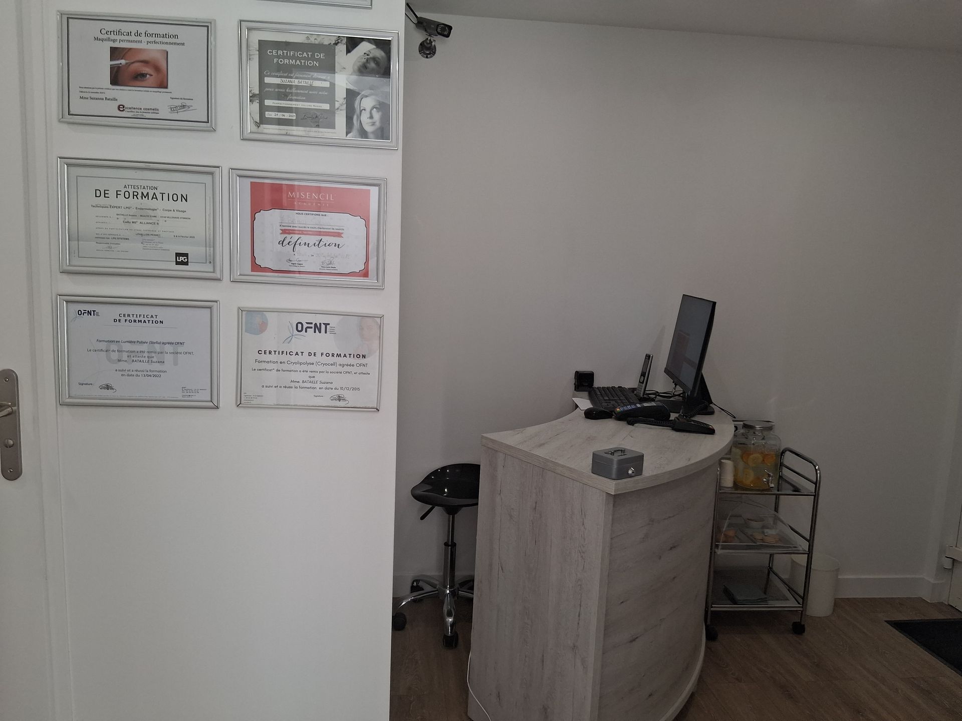 Espace d'accueil avec bureau, ordinateur et certifications au mur.