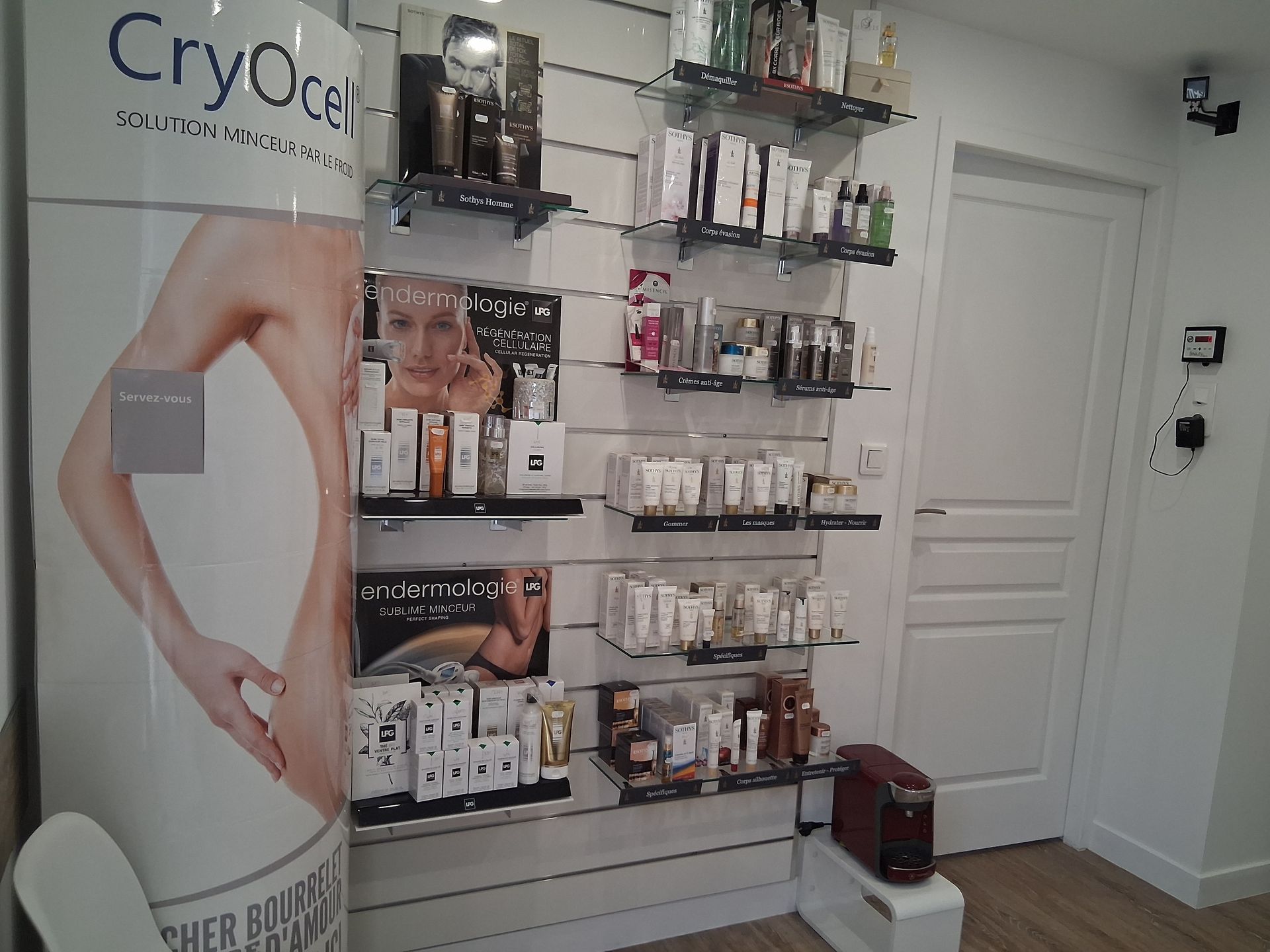 Produits de beauté exposés sur des étagères ; panneau promotionnel avec un corps de femme ; pièce blanche avec une porte.