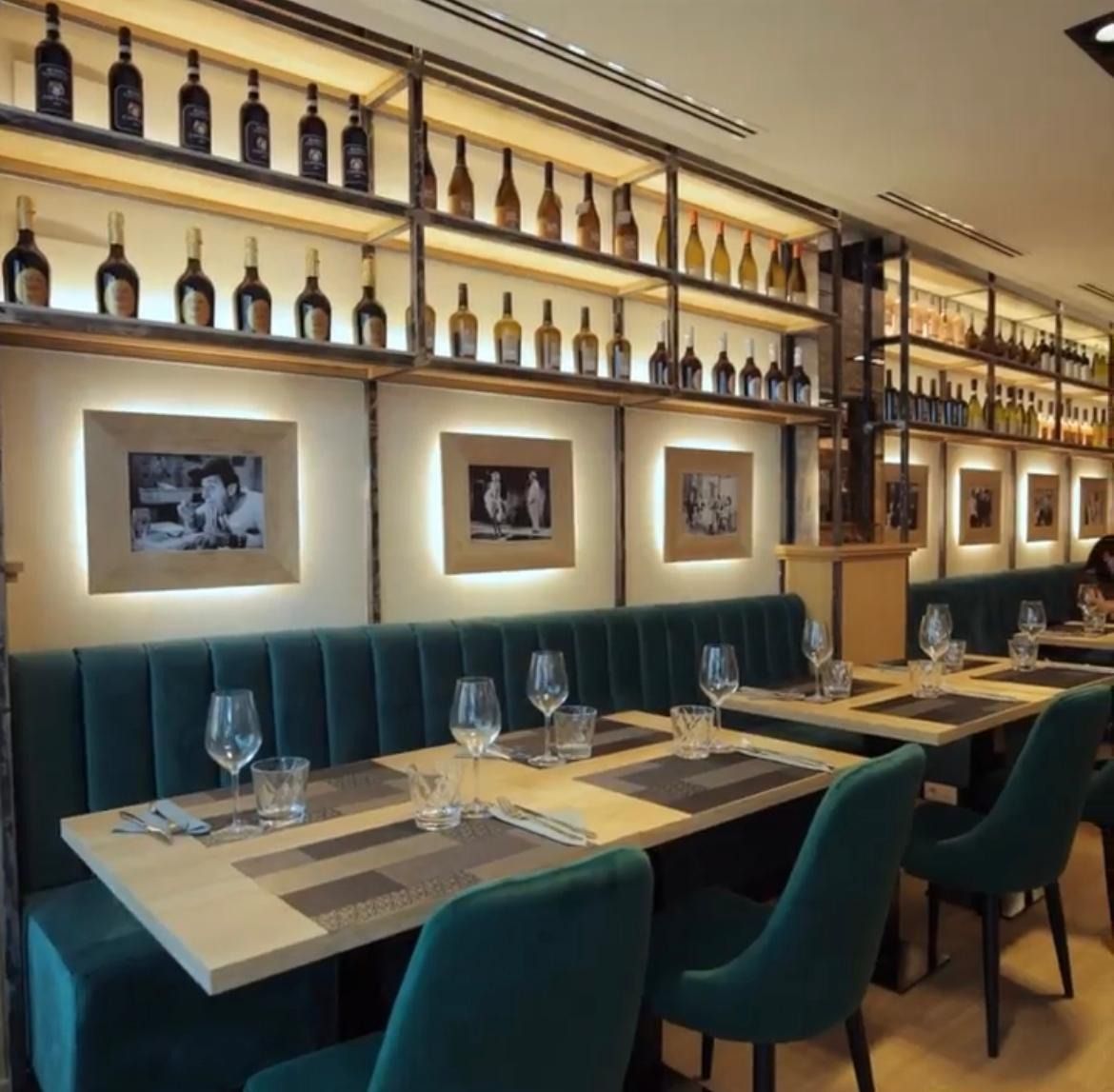 Un restaurante con mesas, sillas y botellas en los estantes.