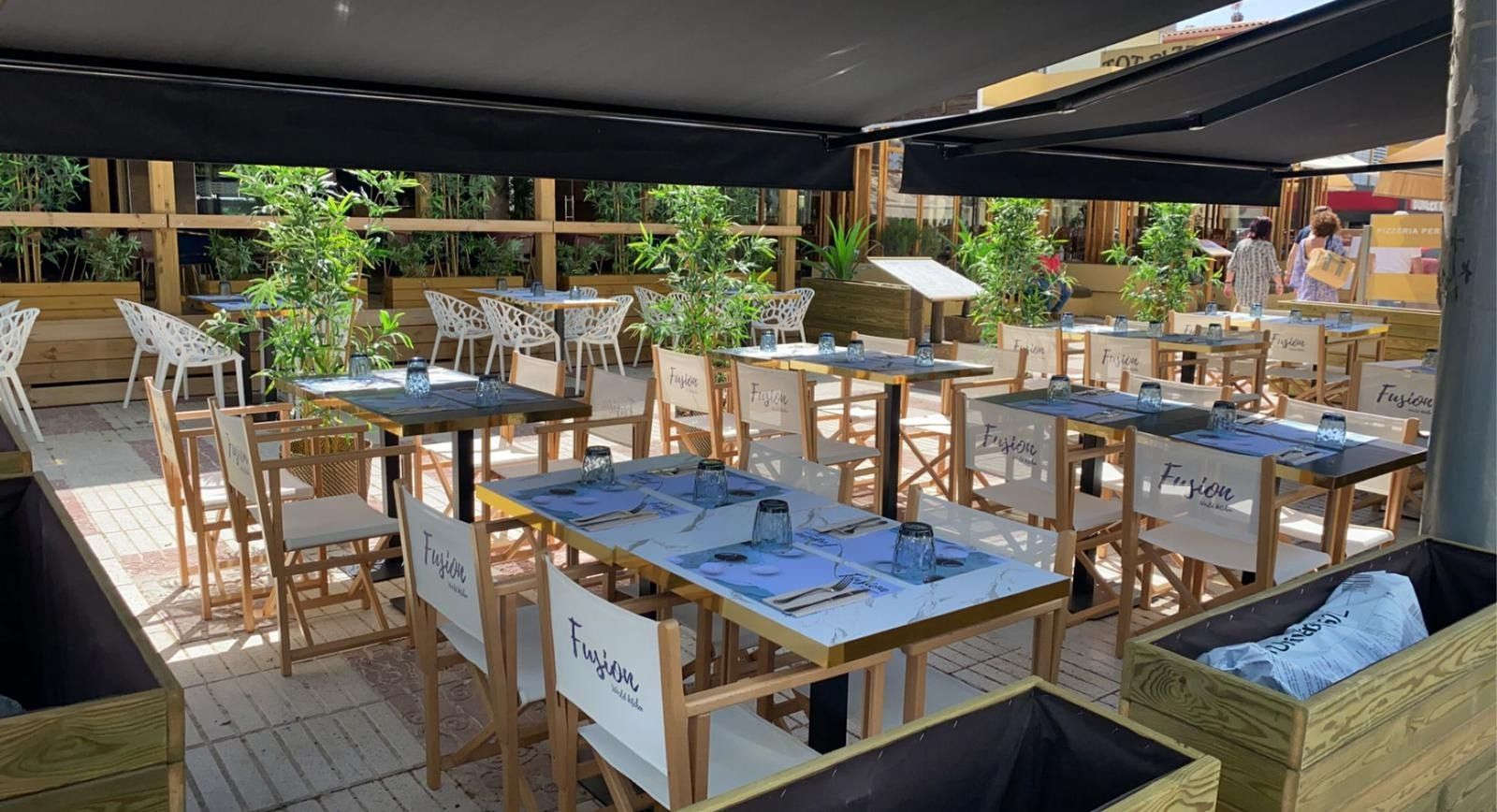 Un restaurante lleno de mesas y sillas bajo un toldo.