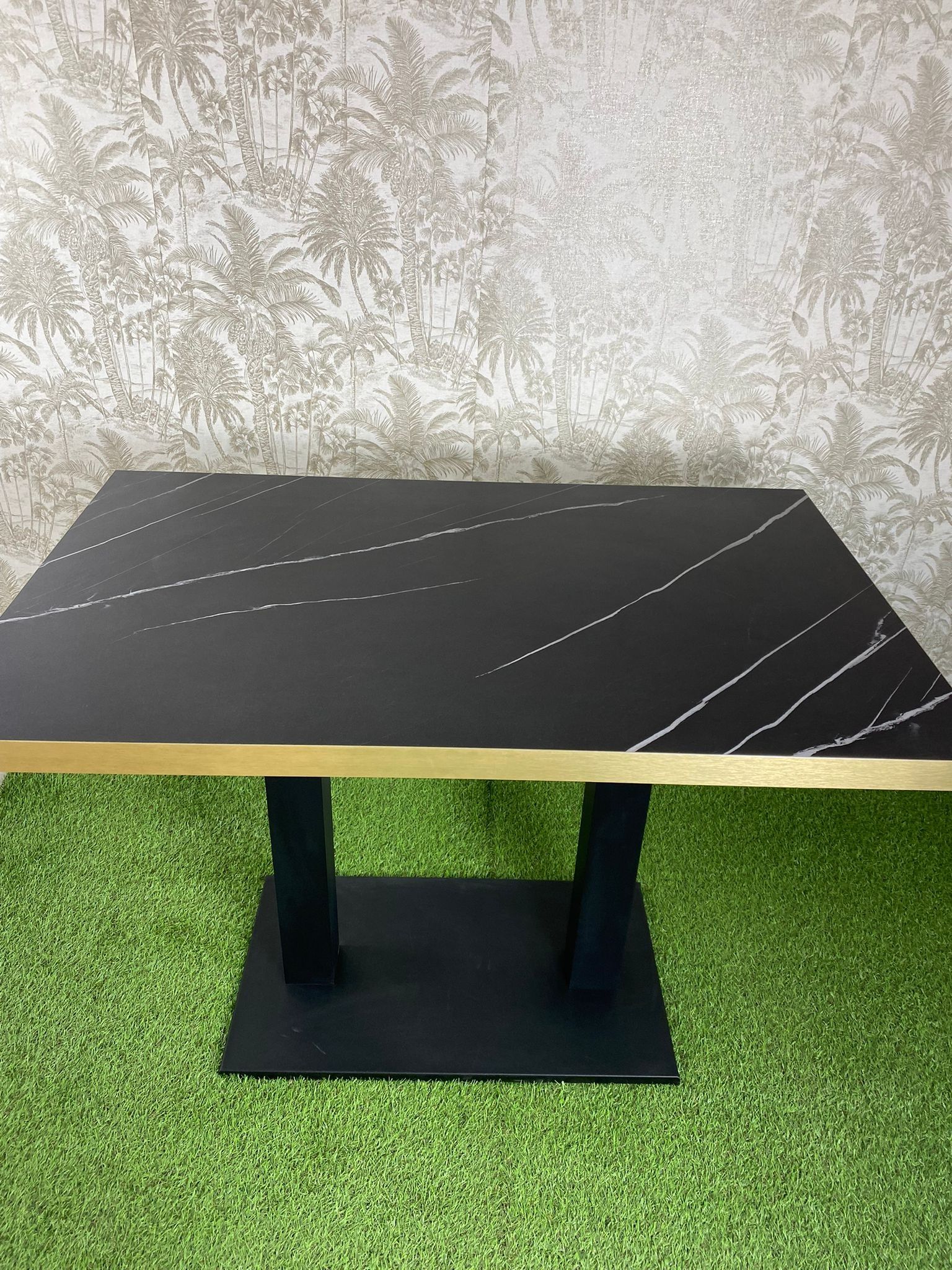 Una mesa negra y dorada reposa sobre una alfombra verde.
