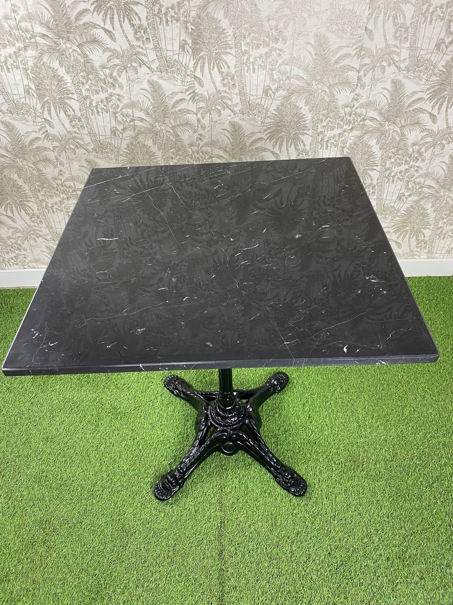 Una mesa negra está colocada encima de una alfombra verde.