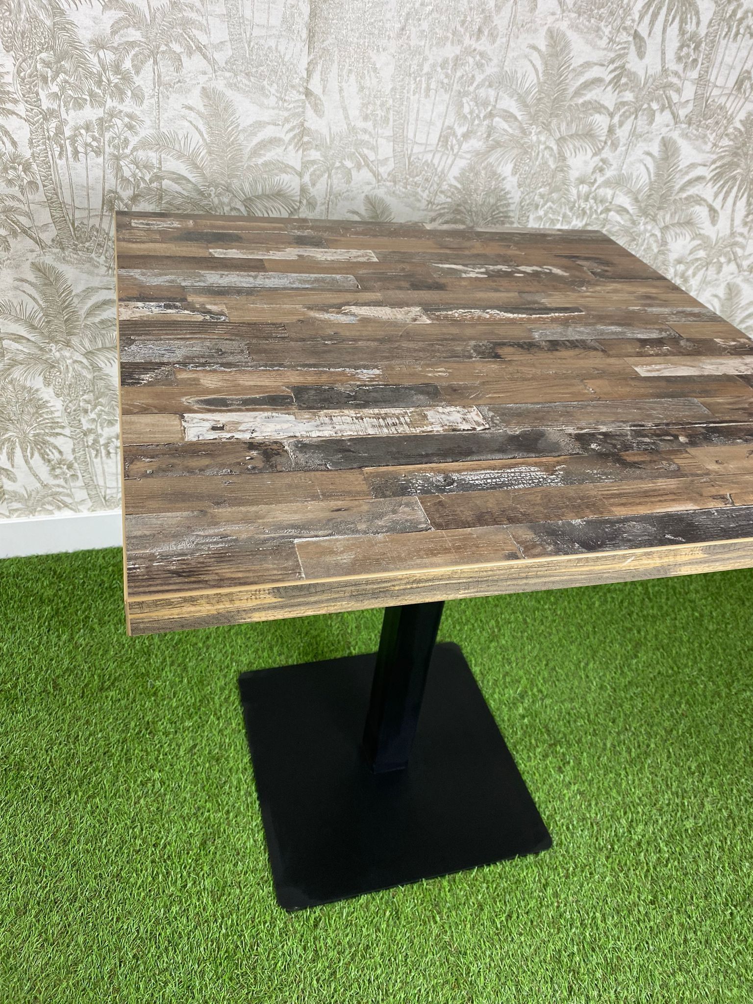 Una mesa de madera está colocada encima de un exuberante campo verde.