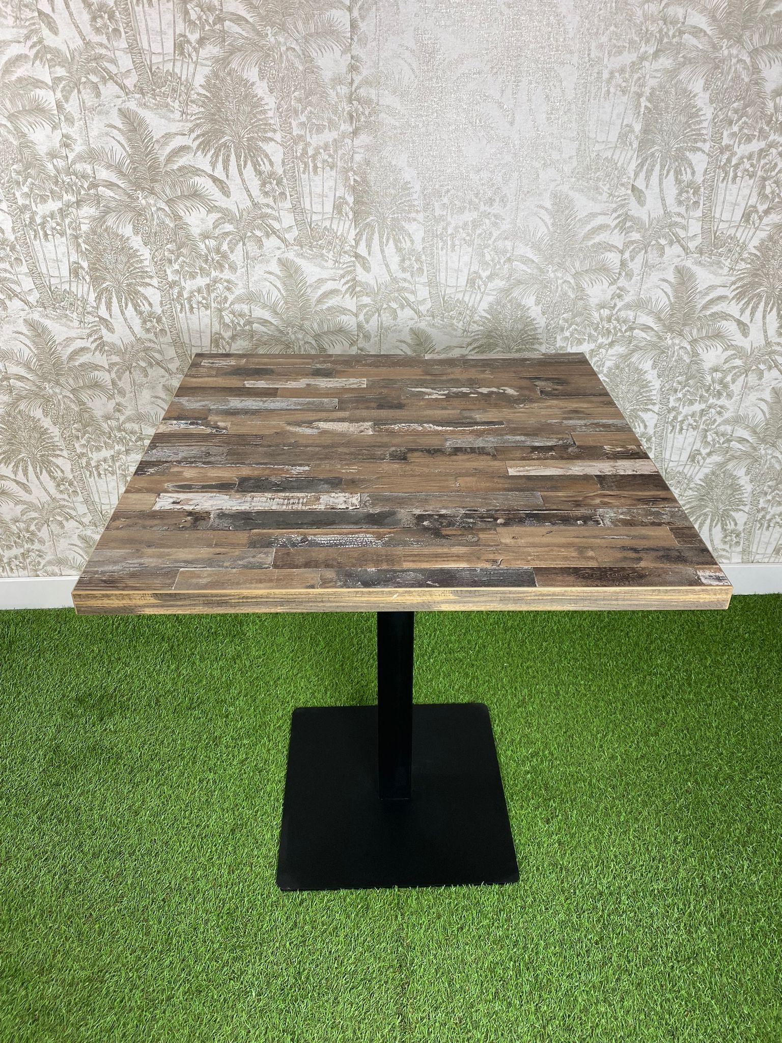 Una mesa de madera está colocada encima de un exuberante campo verde.