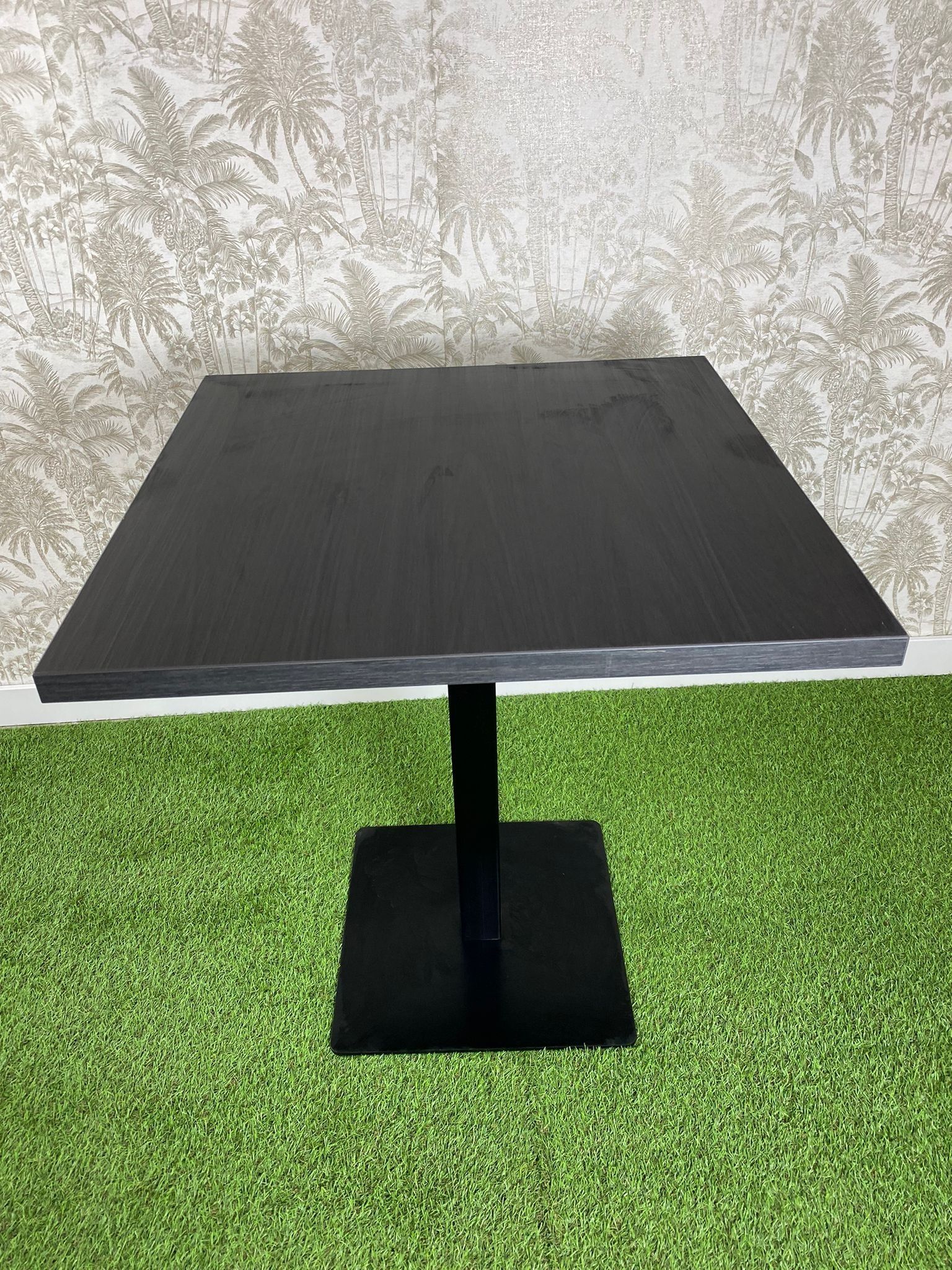 Una mesa negra está colocada encima de una alfombra verde.