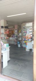 Farmacista che mostra la confezione di un farmaco a un cliente al banco della farmacia