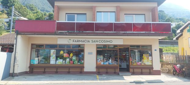 Farmacista in camice bianco controlla le scatole dei medicinali su uno scaffale della farmacia con un tablet