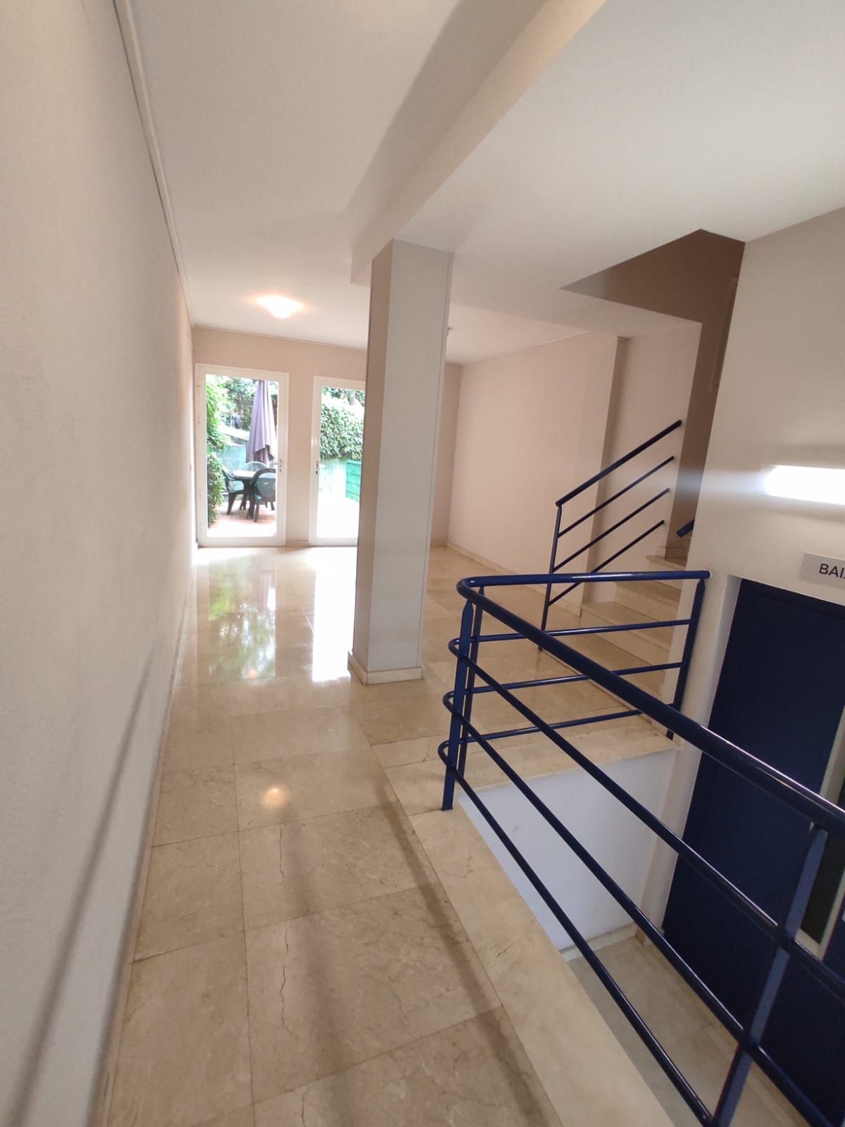 Persona con botas amarillas lavando a presión un patio de ladrillos al lado de un jardín.