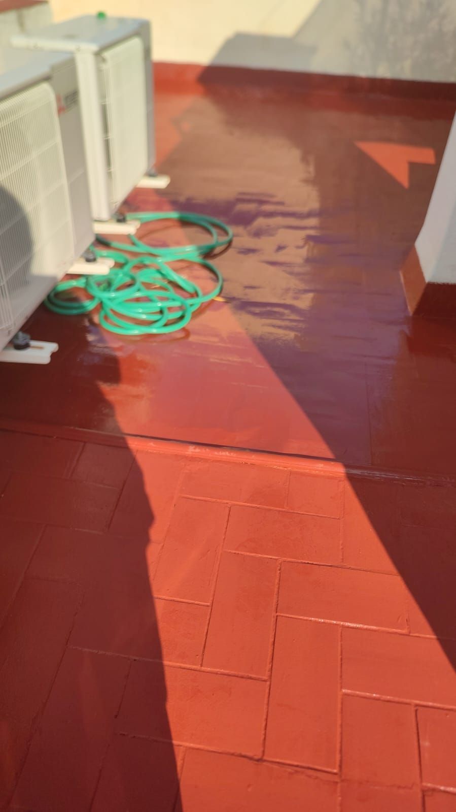Persona trapeando un piso gris con un trapeador azul y blanco, usando sandalias en una habitación con grandes ventanas.