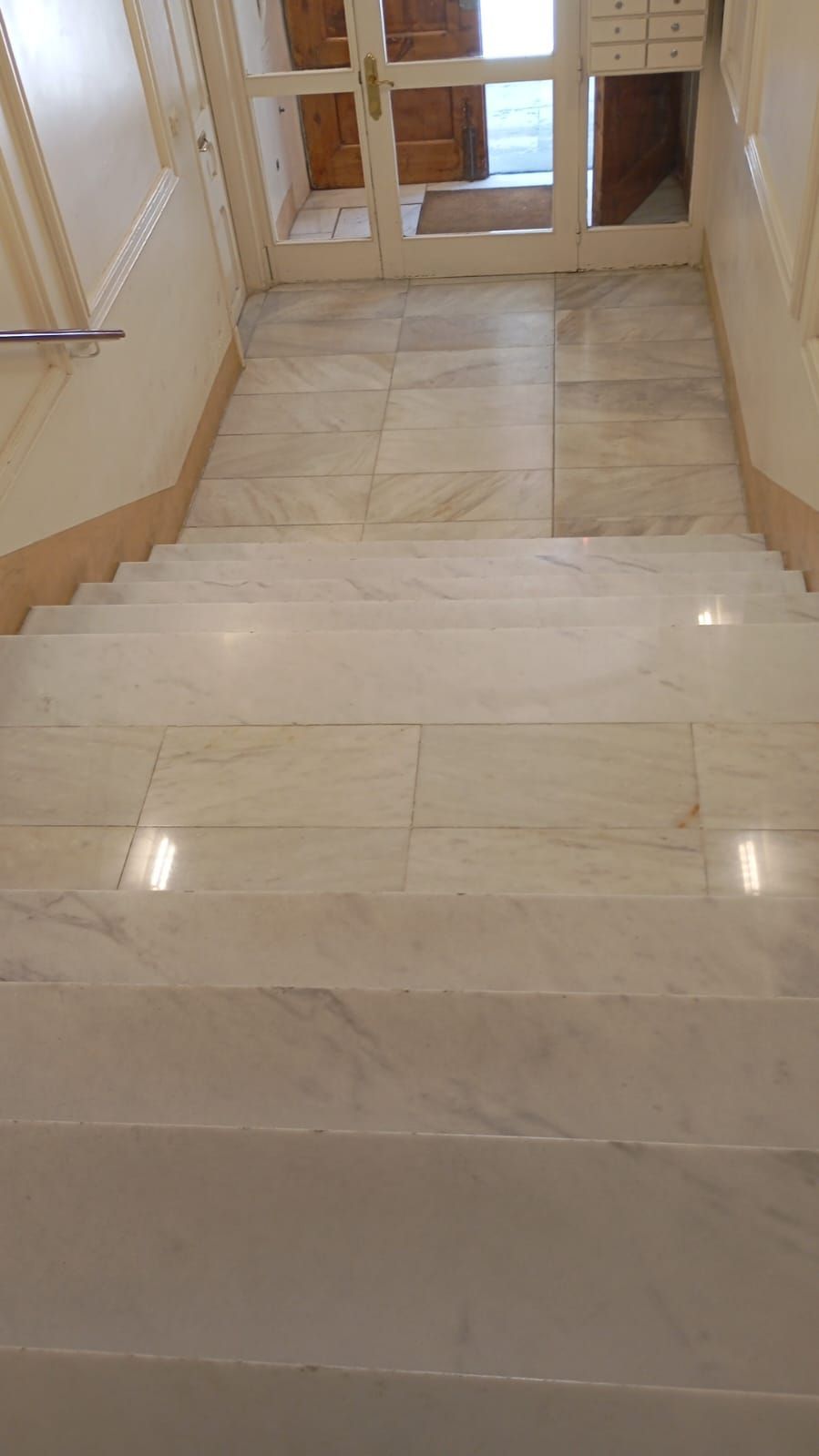 Personal de limpieza de oficinas quitando el polvo de los escritorios; vistiendo overoles azules y guantes verdes.