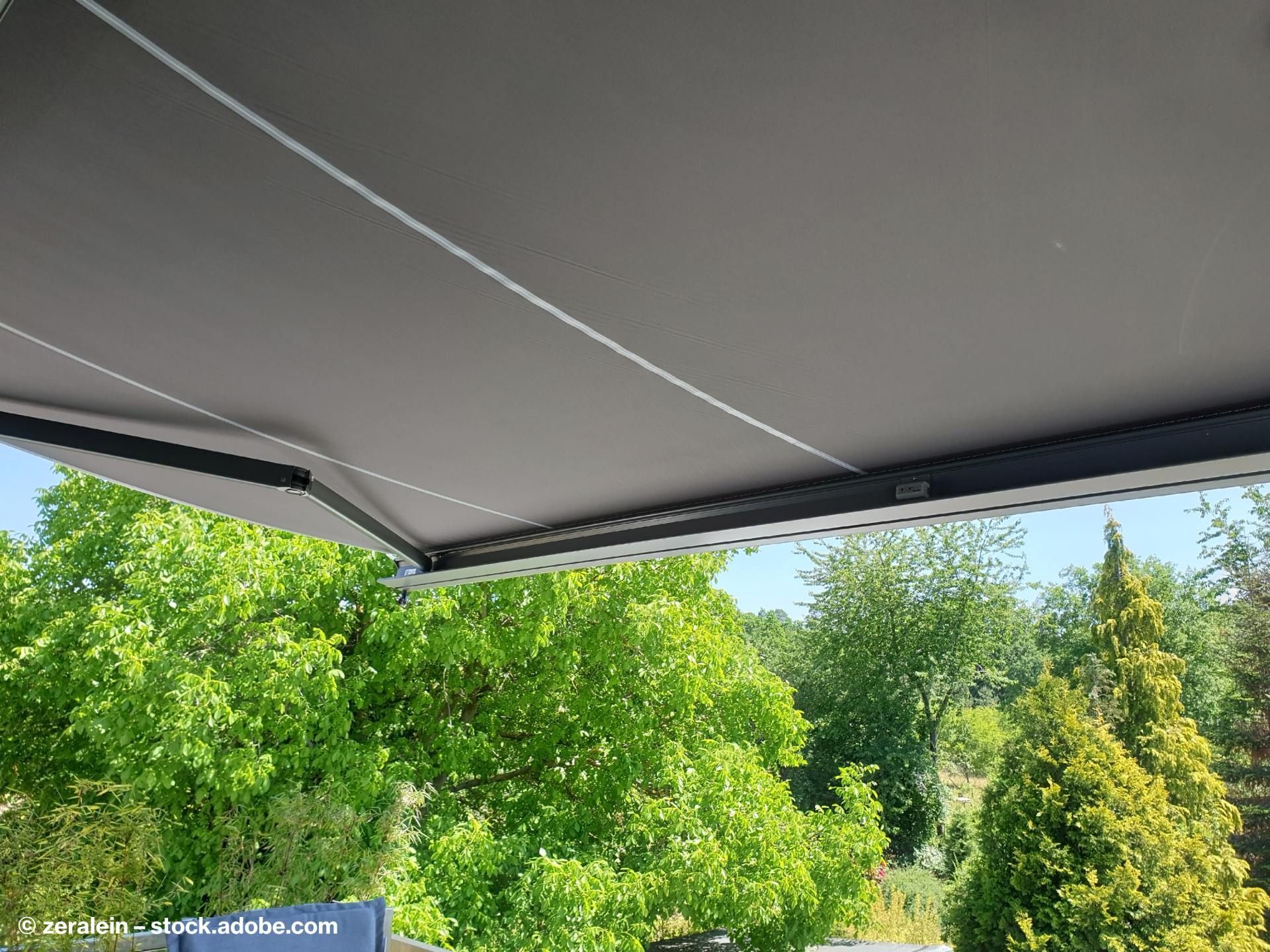 Eine dunkle Markise über der Terrasse eines Hauses