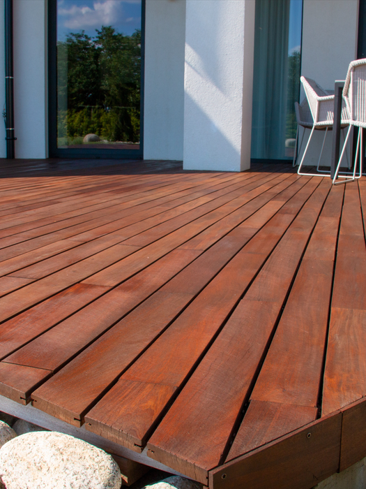 Une terrasse en bois avec des rochers devant un bâtiment