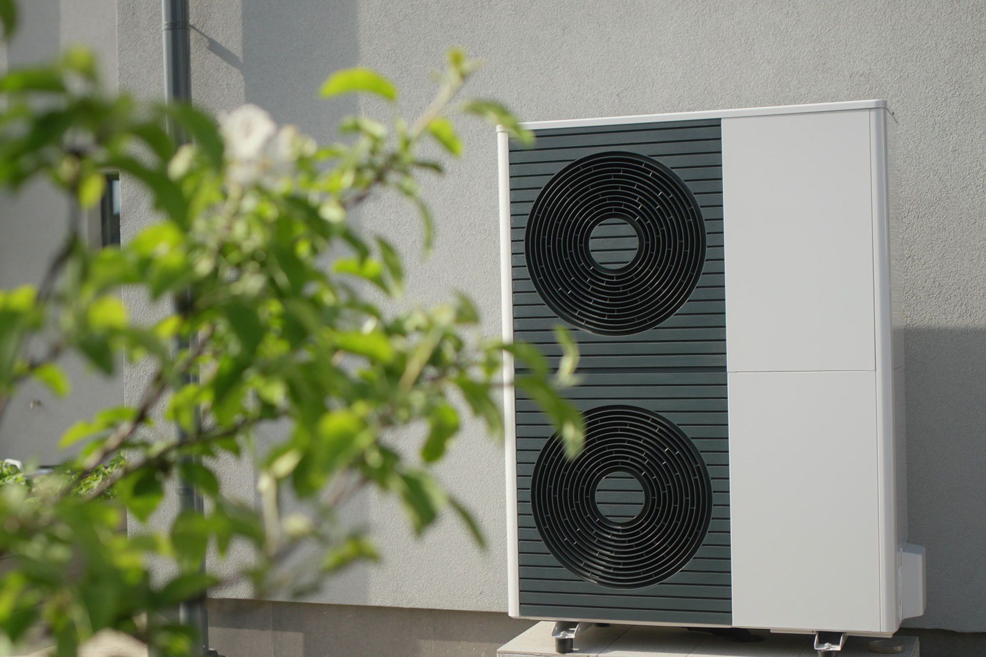 Eine große Klimaanlage steht außerhalb eines Gebäudes neben einem Baum.