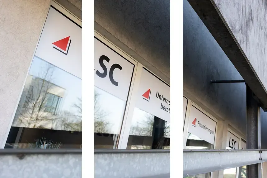 Die Fenster des Bürogebäudes spiegeln das SC-Logo und das rote Dreiecksschild im Glas wider.