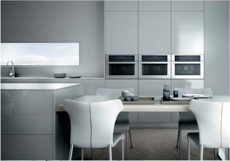 Una cocina con electrodomésticos de acero inoxidable y sillas blancas.