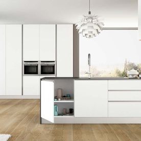 Una cocina con gabinetes blancos, pisos de madera y un fregadero.