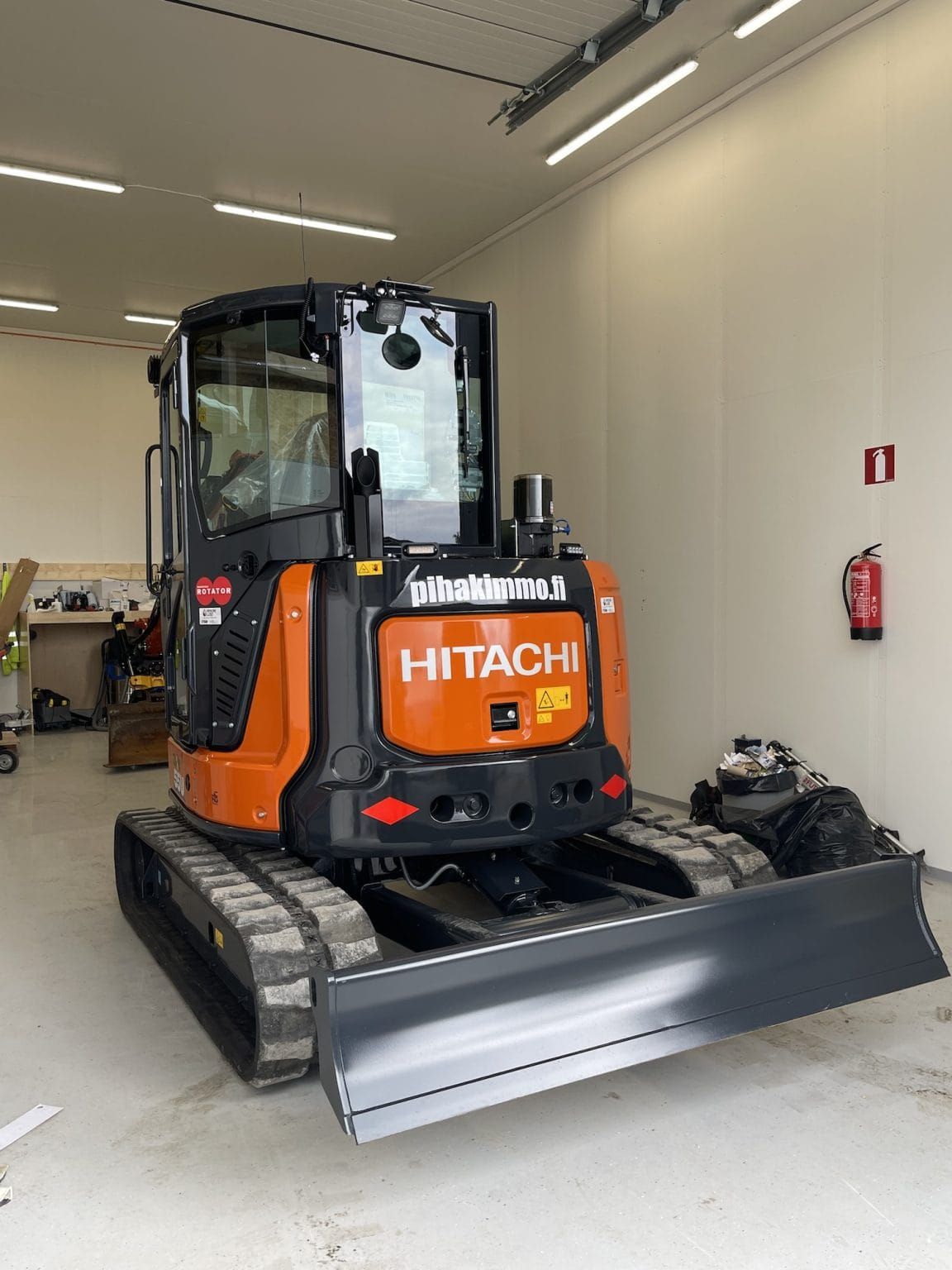 Oranssi Hitachi-minikaivinkone etuterällä sisätiloissa korjaamon autotallissa.