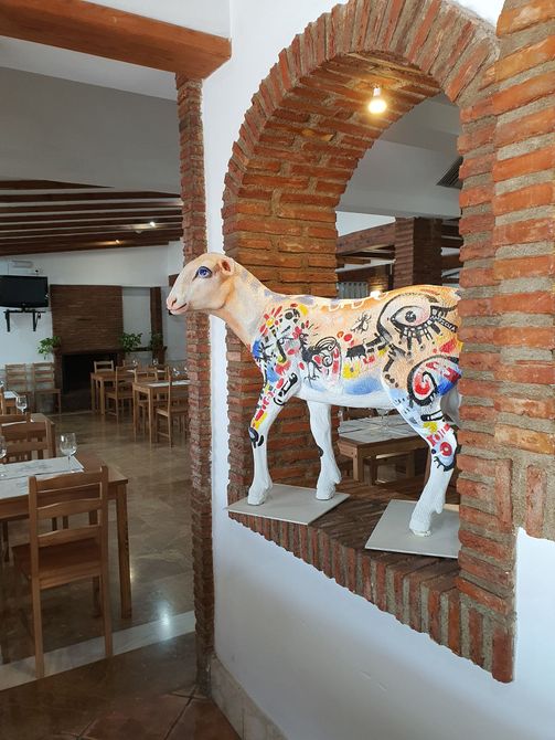 Una estatua de una oveja está sentada en una cornisa en un restaurante.