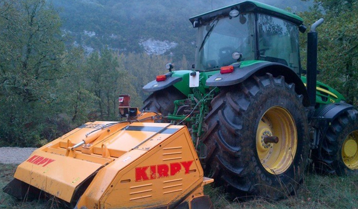 Un tracteur équipé d'un accessoire Kirpy, broyeur de pierre.