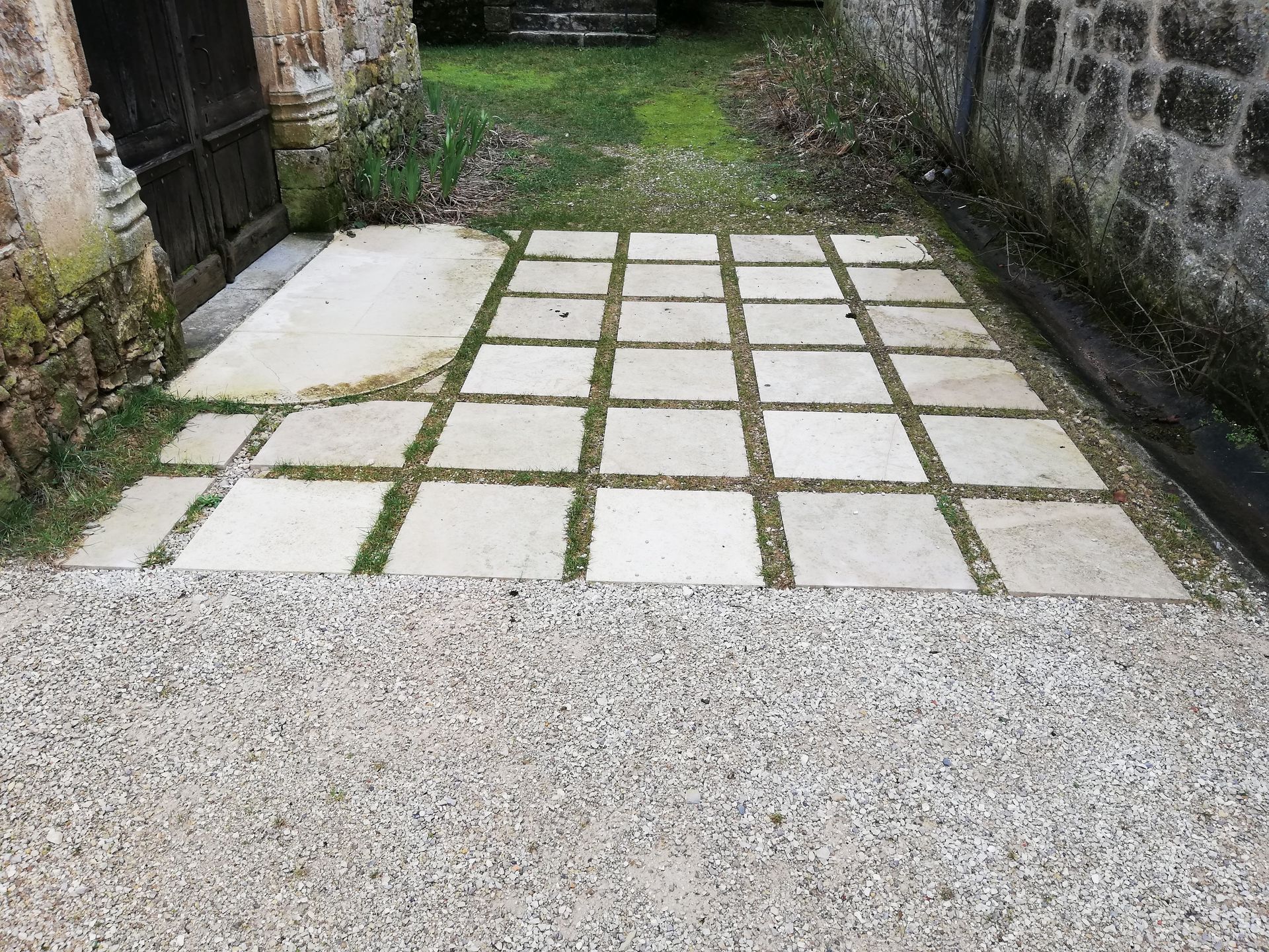 Travaux routiers en cours ; surface asphaltée avec un ouvrier et un rouleau compresseur en arrière-plan.