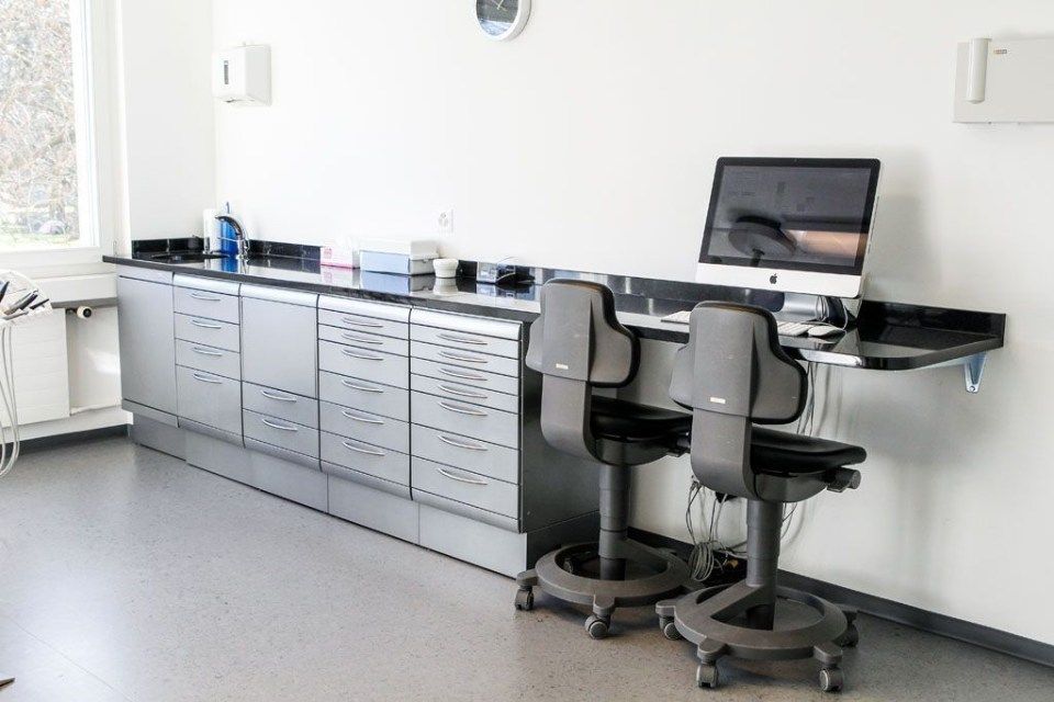 Ein Arbeitsplatz im zahnärztlichen Labor mit Stühlen, Computer und Sideboard