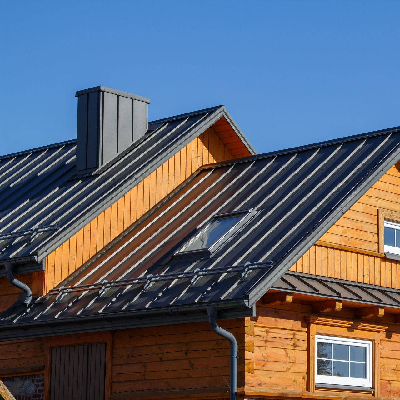 Une maison en bois avec un toit en métal gris foncé.