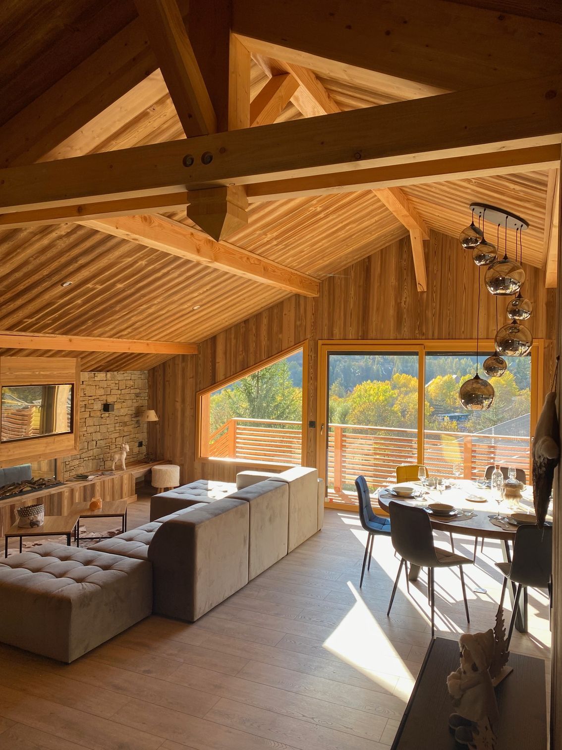 Intérieur de cabane en bois moderne et confortable, avec un grand canapé d'angle gris.