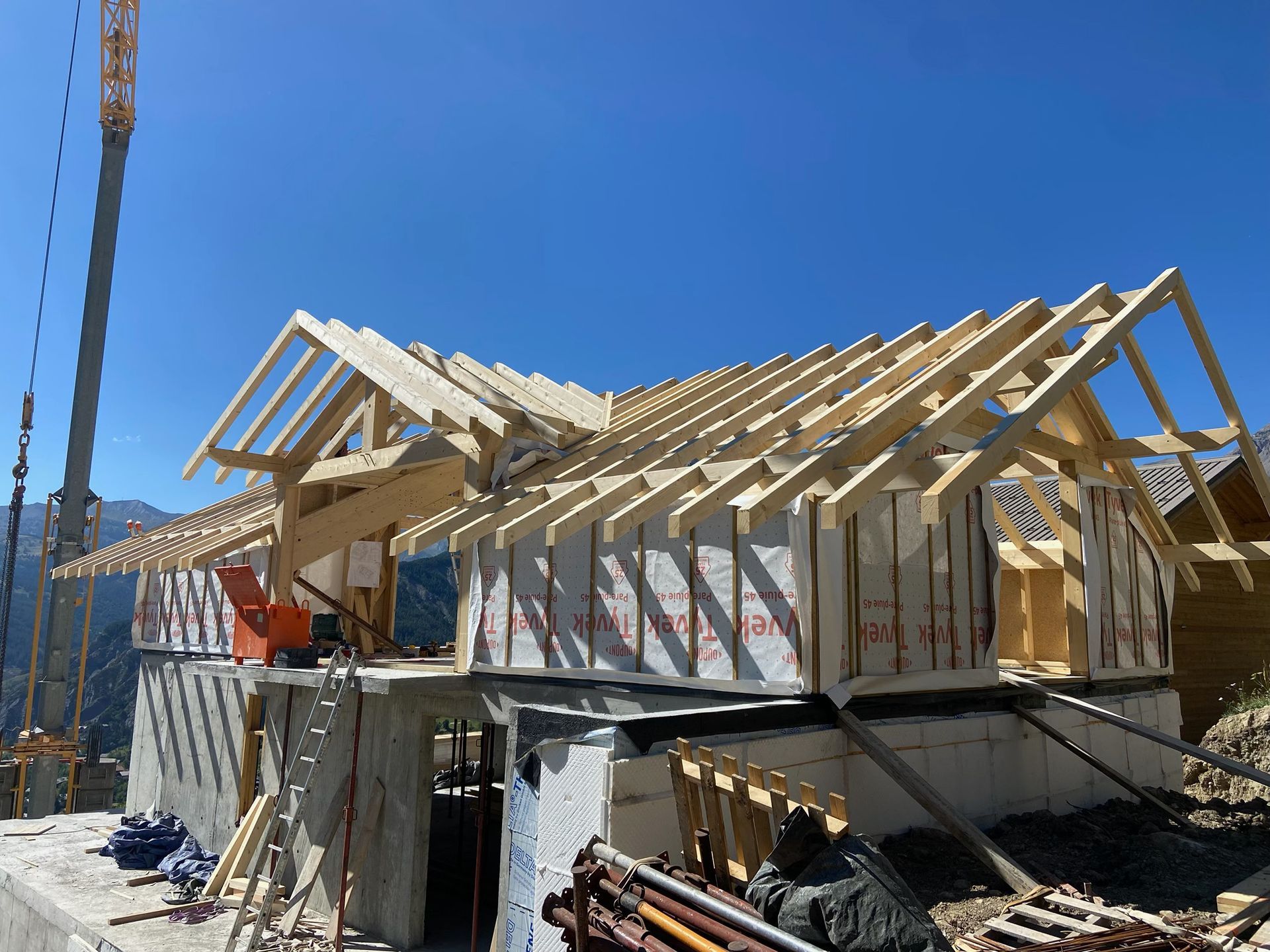 Maison en construction avec charpente en bois et échafaudages
