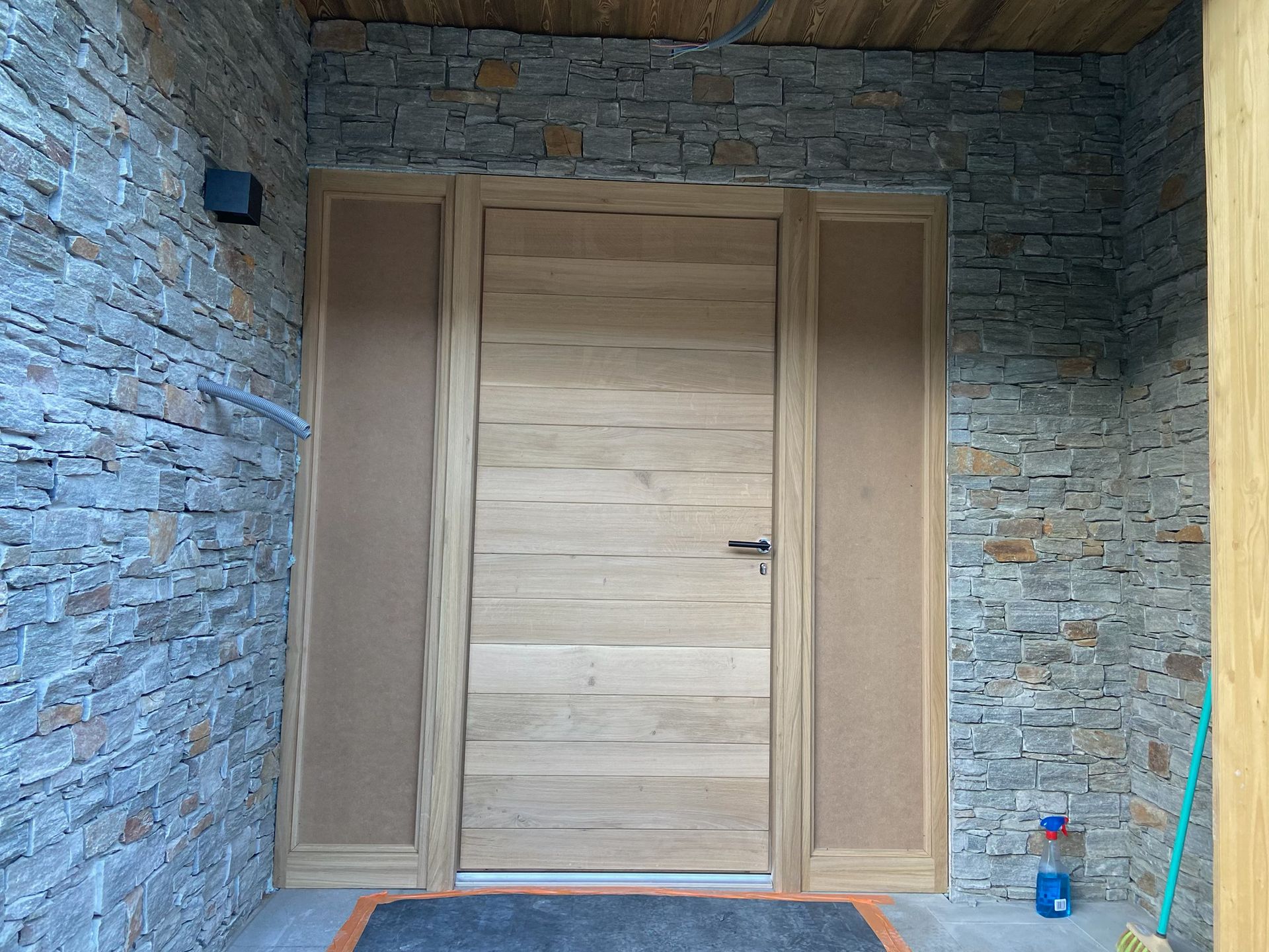 Porte d'entrée en bois encastrée dans un porche en pierre.