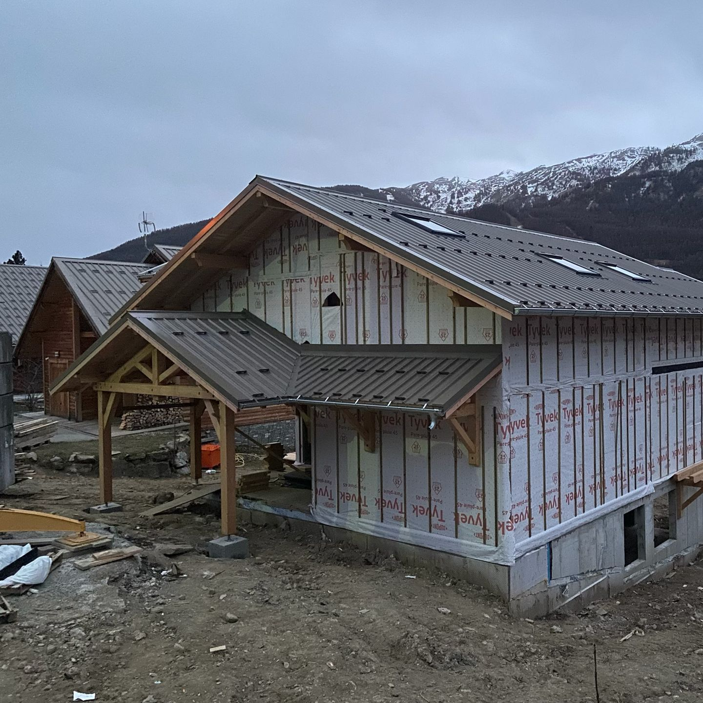 Une maison en construction, à ossature bois et toiture métallique grise
