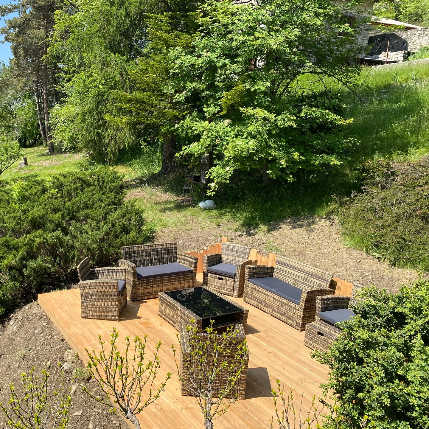 Une cabane en bois à deux étages avec une terrasse surélevée se dresse sur un flanc de colline.