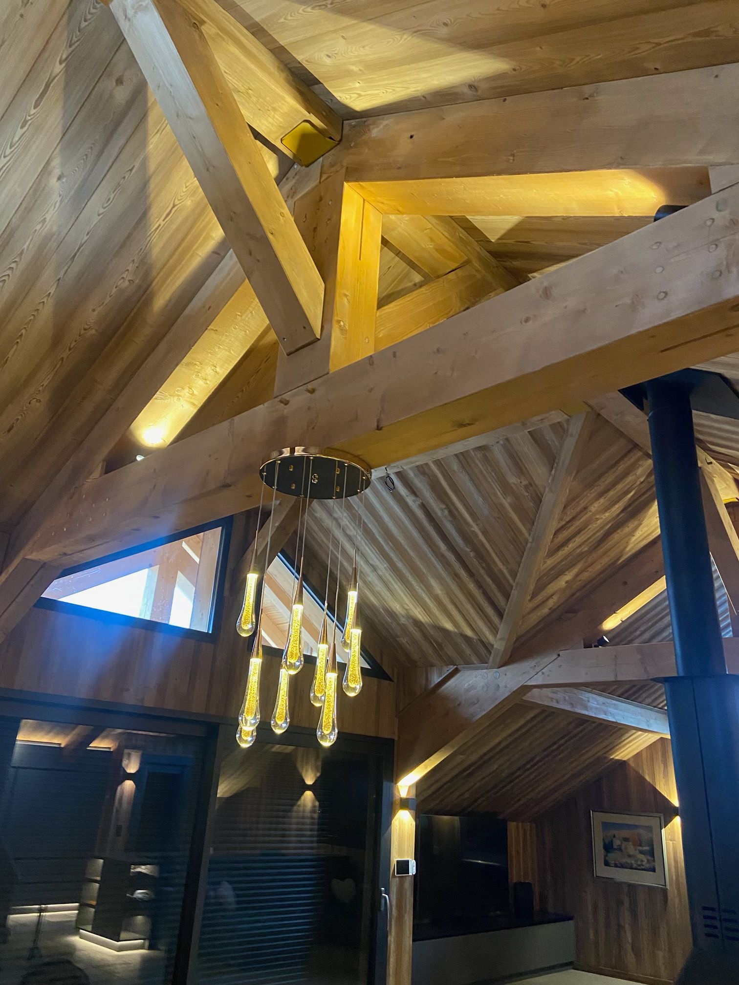 Intérieur de chalet en bois avec poutres apparentes, luminaires suspendus et plafond mansardé