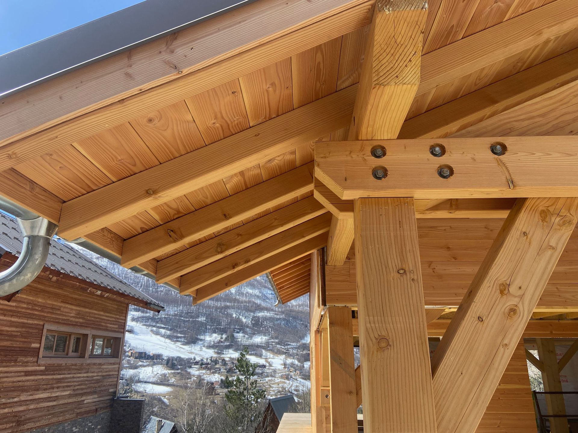 Gros plan sur une construction à ossature bois montrant une poutre de soutien et des chevrons en bois.
