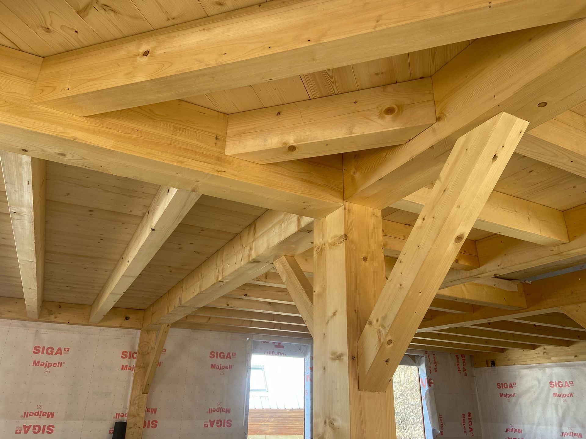 Charpente intérieure en bois avec poutres et fermes de toit apparentes dans une maison en construction